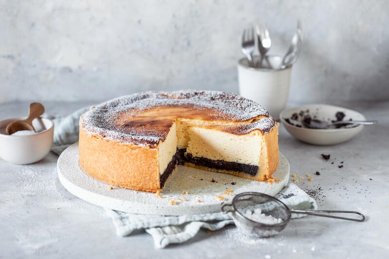 Käsekuchen mit Mohnschicht angeschnitten auf einem Teller