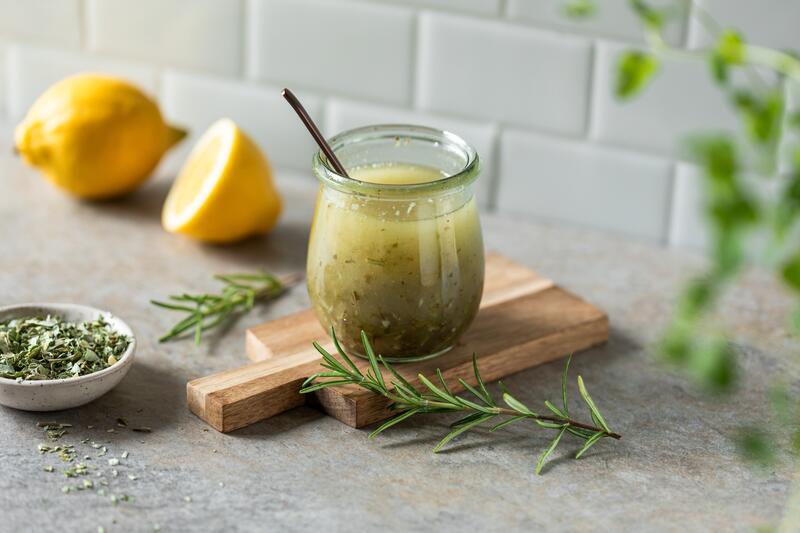Kräuter-Marinade in Glas auf Holzbrett mit angelegten Kräutern