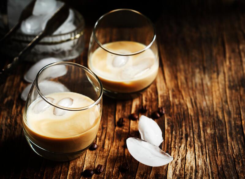 Zwei Gläser mit Baileys auf Eis auf einem Holztisch
