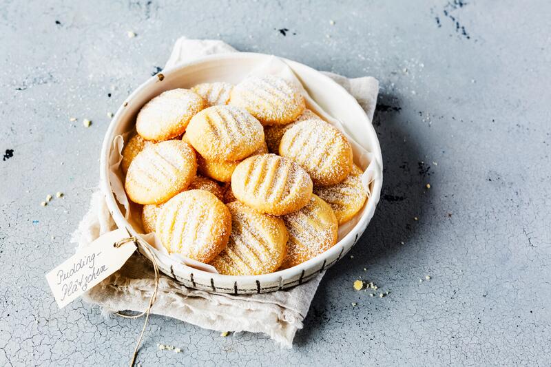 Puddingplätzchen mit Puderzucker auf weißem Teller