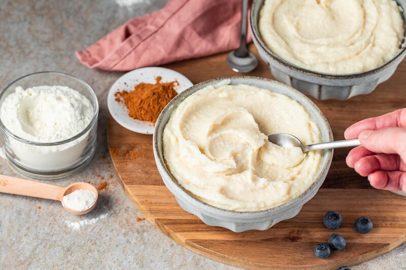 2 Schüsseln mit Grießpudding, eine Hand hebt einen Teelöffel der Masse heraus