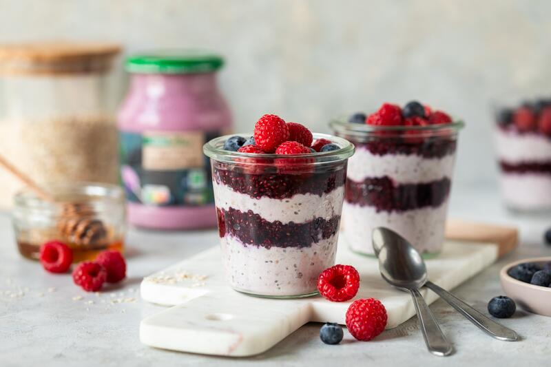 Zwei Gläser mit Overnight-Oats und Beeren-Schichten