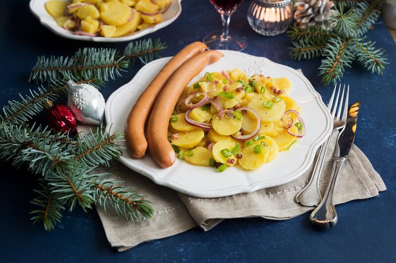 Kartoffelsalat mit Würstchen auf Teller Besteck
