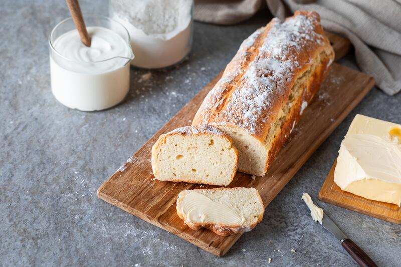 Preoteinbrot auf einem Holzbrett angeschnitten mit Butter