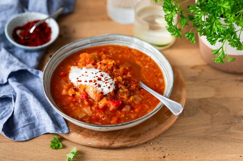 Tiefer Teller mit roter Kohlsuppe, darauf etwas weiße Creme mit Chilipulver