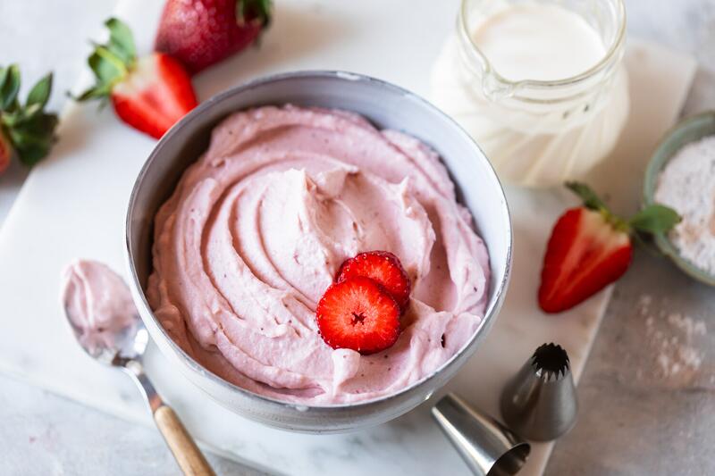 Schüssel mit rosa Schlagsahne und frischen Erdbeeren
