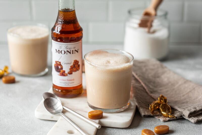 Gläser mit milchigem Getränk und daneben Karamell Sirup