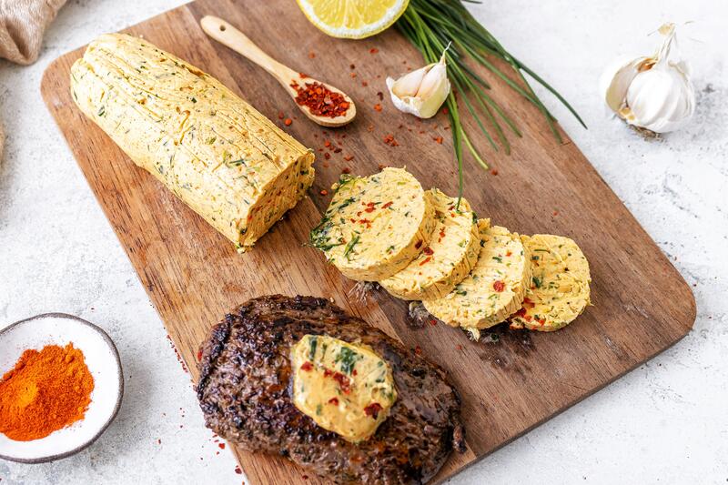 Brett mit aufgeschnittener Kräuterbutter und einem Steak
