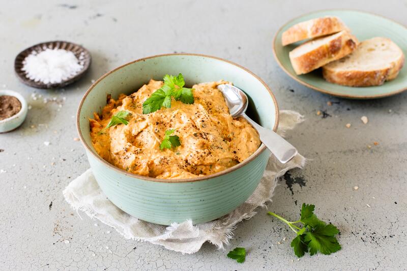Eine Schale mit Dip und einem Löffel, daneben Brot