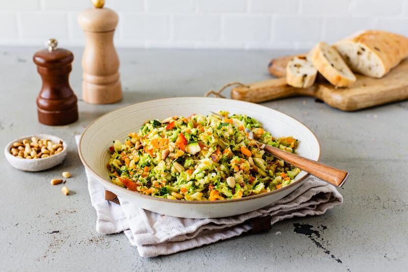 Bunter Tapas-Salat aus dem Thermomix® auf großem runden Teller mit angestelltem Ciabatta auf Holzbrettchen