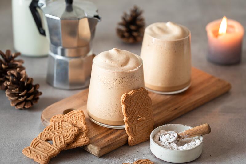 2 Gläser Spekulatius-Creme auf einem Holzbrett mit Keksen