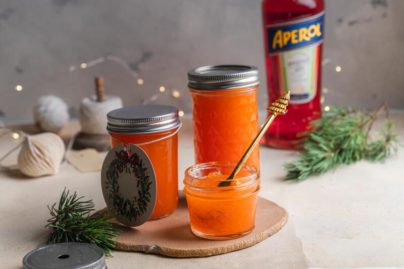 Einmachgläser mit orangenem Gelee, im Hintergrund eine Aperolflasche