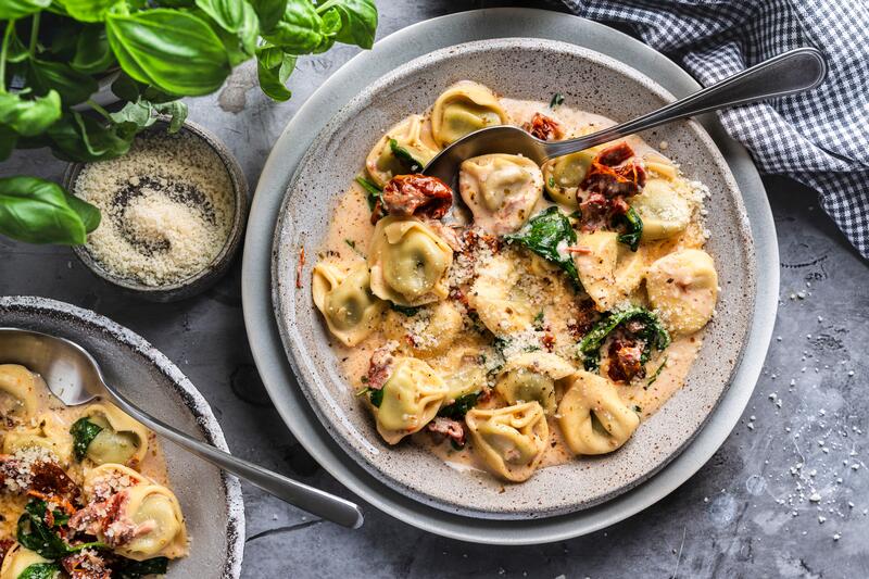 Schüssel mit Tortellini in cremiger Sahnesoße und getrockneten Tomaten