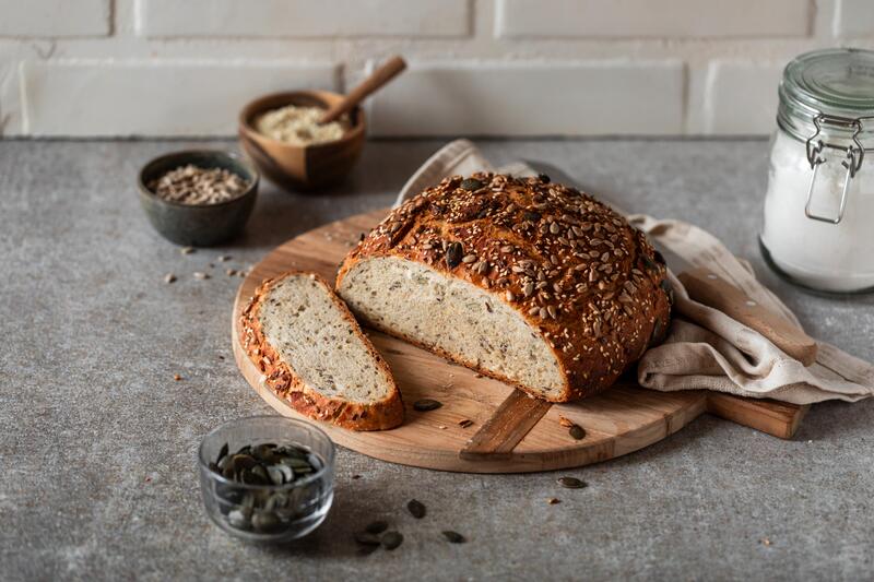Aufgeschnittenes Brotlaib mit vielen Körnernauf eiinem Holzbrett
