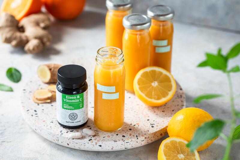 Shots mit Orange und Ingwer, daneben ein Glas mit nahrungsergänzungsmitteln