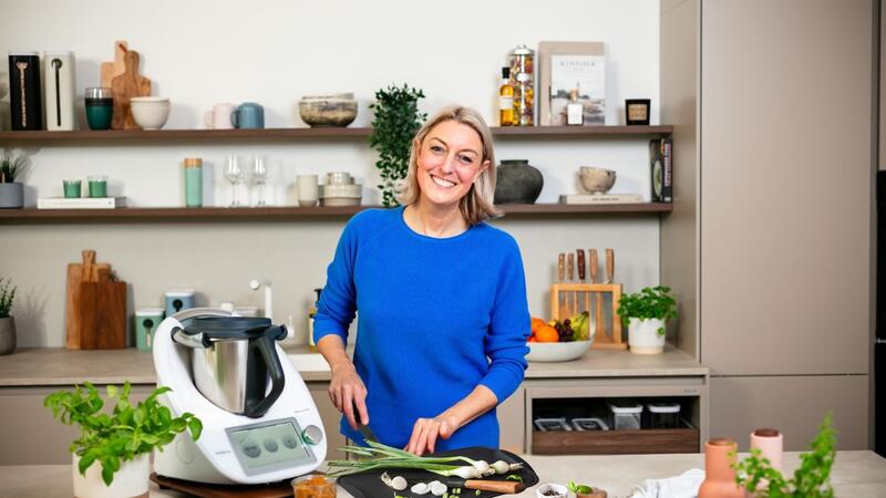 Blonde Frau in einer Küche mit Thermomix®, schneidet Gemüse