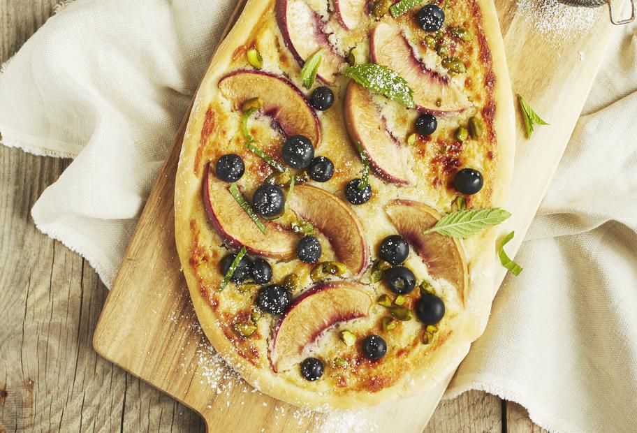 Süße Pizza mit Heidelbeeren und Pfirsichen