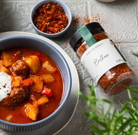 Eine Schale mit Gulasch, daneben ein Glas Balkan-Gewürz, von oben fotografiert