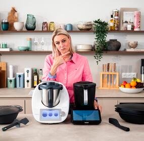 Eine Frau steht hinter zwei Thermomix® Geräten und guckt fragend