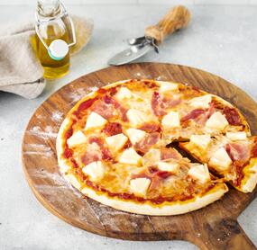 Hawaiipizza, ein Stück wird mit einer Hand angehoben.