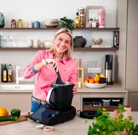 Eine blonde Frau rührt mit dem Spatel im Thermomix® TM7