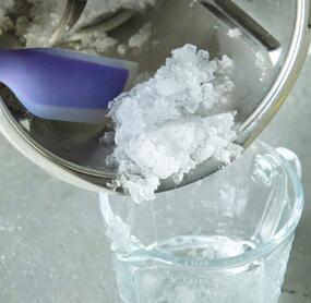 Jemand füllt Crushed Ice aus dem Mixtopf des Thermomix® in ein Glas