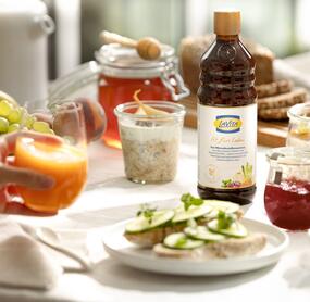 Frühstückstisch mit Obst und Gemüse, ein Glas Saft, eine Flasche LaVita