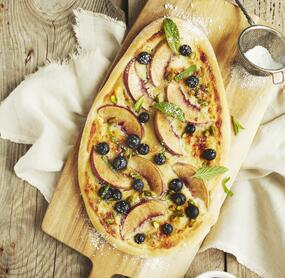 Süße Pizza mit Heidelbeeren und Pfirsichen