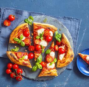 Knusprige Pinsa von oben fotografiert auf blauem Untergrund