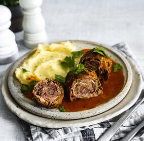 Kohlrouladen mit Kartoffelpüree und brauner Soße auf einem hellen Teller