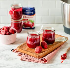 Rote Marmelade in Gläsern, daneben Erdbeeren