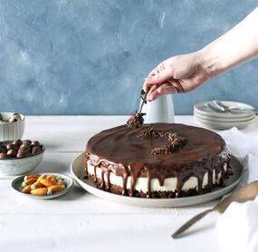Torte mit Schokoguss, jemand gibt Streusel darauf