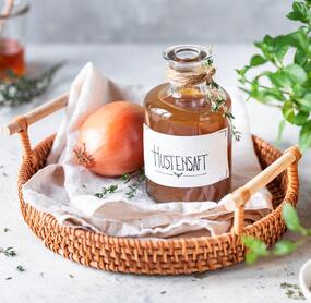 Eine Flasche Hustensaft und eine Zwiebel in einem Korb