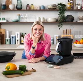 Blonde Frau in einer Küche auf die Arbeitsplatte gestützt, neben dem Thermomix®