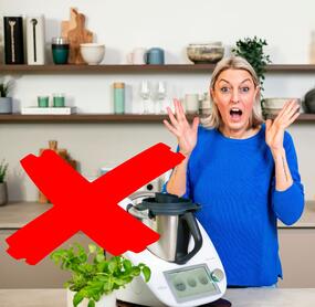 Blonde Frau steht neben dem Thermomix® und hebt erschrocken die Hände