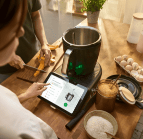 Eine Frau steht vor dem Thermomix® TM7 und bedient das Display