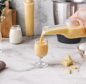 Jemand gießt Likör in ein Glas