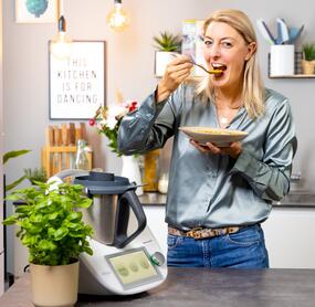 Blonde Frau mit einem Thermomix® und einem Teller Suppe