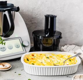 Der Thermomix® TM6, daneben der Wunder Slicer Aufsatz und eine Auflaufform mit Kartoffelgratin